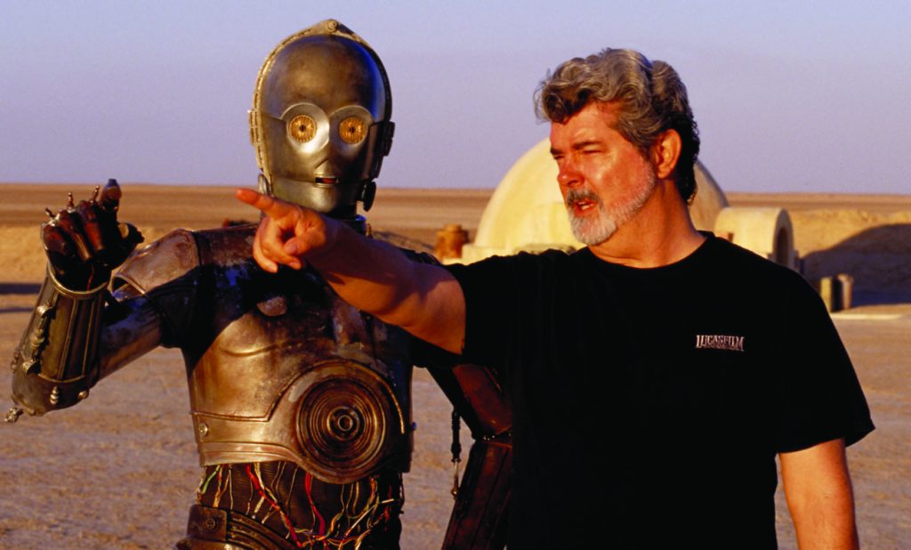 ** FILE ** In this undated publicity photo released by Lucasfilm Ltd. & TM, director George Lucas directs actor Anthony Daniels, who plays the robot C-3PO, in "Star Wars II: Attack of the Clones," on location in the Tunisian desert. Dozens of groundbreaking technologies were developed for the production of the Star Wars movies. ThereÕs no mistaking the similarities. A childhood on a dusty farm, a love of fast vehicles, a rebel who battles an overpowering empire, George Lucas is the hero he created, Luke Skywalker. (AP Photo/Lucasfilm Ltd. & TM, LisaTomasetti)