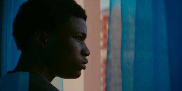 bir erkek perdelerin arkasından camdan dışarıya bakıyor.