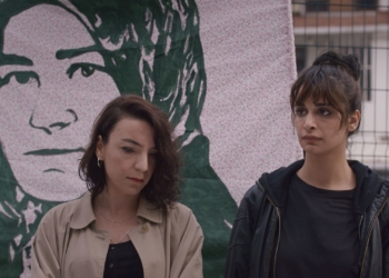 İki kadın bir pankartın önünde duruyor