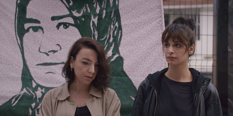 İki kadın bir pankartın önünde duruyor