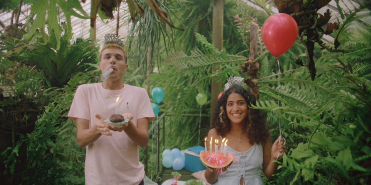 Bir kadın ve erkek ormanda ellerinde mum yanan patlar tutarak kameraya gülümsüyor