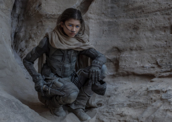 Zendaya yere çömelmiş bir şekilde karşıya doğru bakıyor