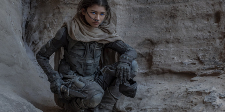 Zendaya yere çömelmiş bir şekilde karşıya doğru bakıyor